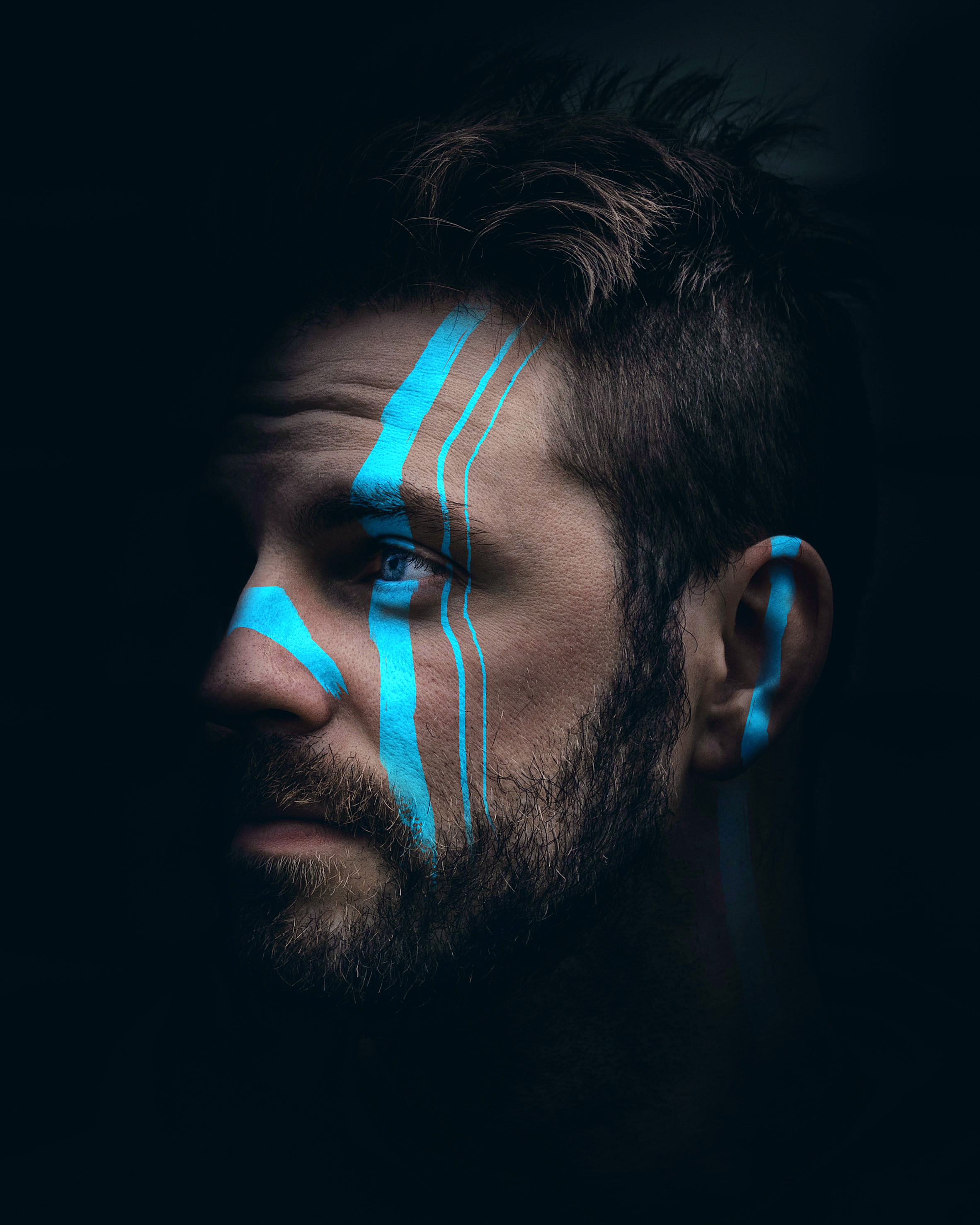 A striking portrait of a man with cyan paint stripes across his face — Pixometry brand image